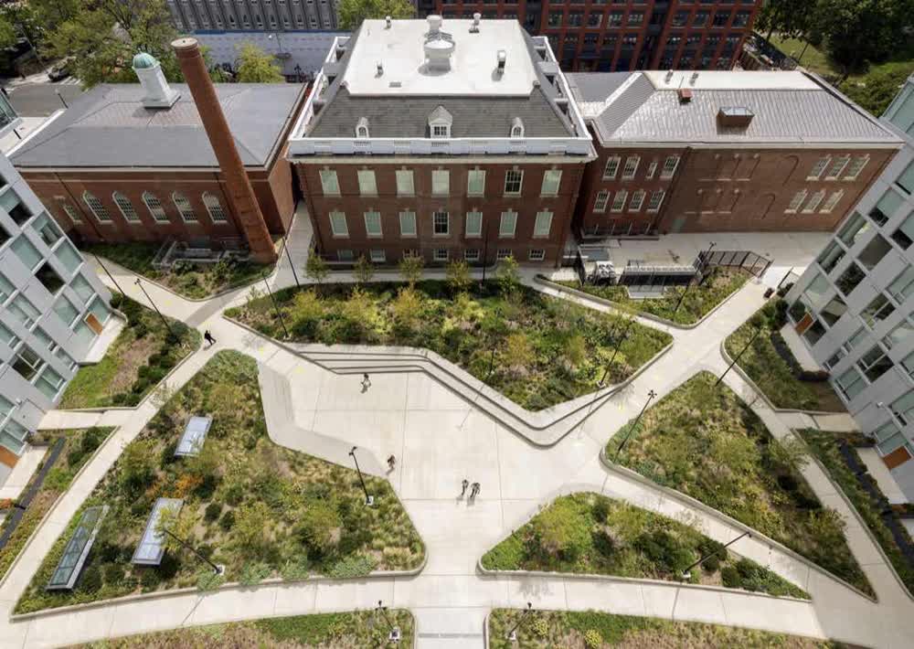 Aerial view of a courtyard with radiating paths between a historic brick building and new residential wings